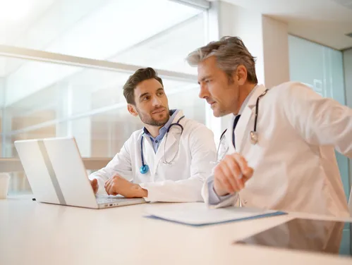 two people working with a laptop in a hospital