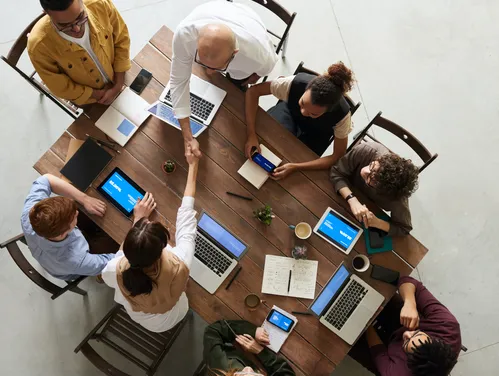 Above table angle. People around a table, two people shaking hands.