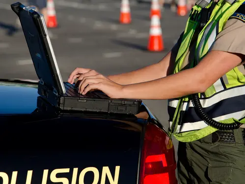 public safety employee using a laptop near an emergency vehicle