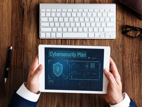 man at a desk using a tablet to make a cybersecurity plan